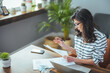 © Dragana Gordic - A beautiful black-haired businesswoman sitting in her home office and filling out bills. Busy business woman. The concept of finance