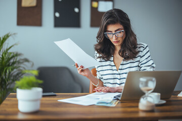 A smart business woman who keeps a paper account using a calculator, an old woman manages the account's finances, calculates the tax on the cash budget, plans to pay off a bank loan debt