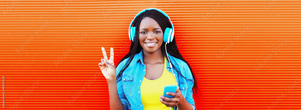 Portrait of happy smiling young african woman in headphones listening ...