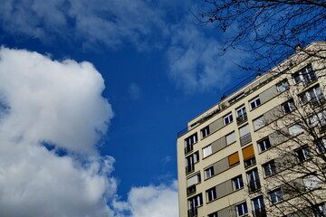 Sticker - Immeubles, ciel bleu avec nuages blancs.