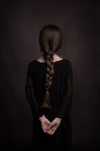 Rear View Of Girl With Long Hair In Braid And Hands On Back In Classic Dark Studio Portrait