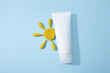White squeeze bottle plastic tube for branding of medicine or cosmetics - daily cream, gel, skin care. Cosmetic bottle container and yellow plasticine modeling clay sun on blue background. Mockup