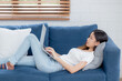 © NT_studio - Young asian business woman smile and work from home with laptop computer online to internet on sofa in living room, freelance girl using notebook on couch with comfort, new normal, lifestyle concept.
