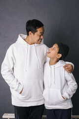 Wall Mural - Silly face expressions of father and son, wearing white hoodie for apparel mock up, isolated on gray background 