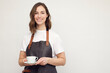 © Martin Villadsen - Beautiful young barista woman looking in camera and smiling, while serving a cup of coffee. Isolated on white background.
