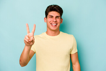 Young caucasian man isolated on blue background showing number two with fingers.