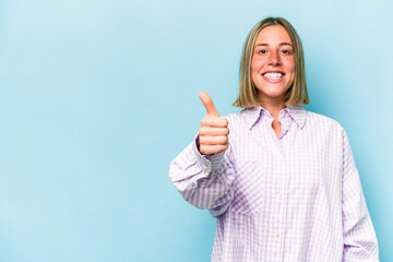 Wall Mural - Young caucasian woman isolated on blue background smiling and raising thumb up