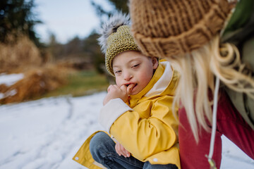 Wall Mural - Boy with Down syndrome with his mother playing with snow in garden.