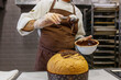 Pasticciere mentre fa colare del cioccolato fondente fuso su un panettone artigianale 