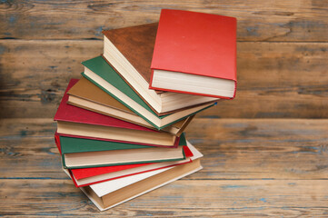 Stack of books on wooden table over rustic background with copy space