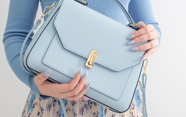 young girl in blue blouse  and pleated skirt with blue handbag on white background