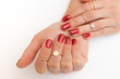 © Alina - Manicure gel polish of red color with sparkles on female hands with rings