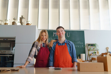 Wall Mural - Young Down Syndrome waiter working with colleague in take away restaurant, social inclusion concept.