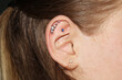 Girl's ear with three ear cartilage piercings and one lobe piercing with beautiful piercing jewelry with crystals of different colors.