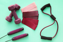 Elastic Bands, Dumbbells, Skipping Rope And Fitness Expander On Color Background