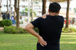© Sanhanat - Back view of man hurts his shoulder and waist at outdoor park. Concept : Health problems, swelling and inflammation, pain. Symptoms of health injury in daily life.