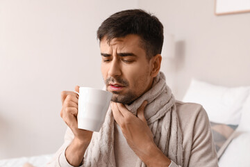 Poster - Ill young man with sore throat drinking hot tea at home