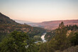 © Cavan Images - A river flows through forested hills at sunset