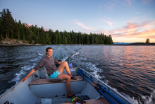 A Young Woman In Steers A Small Boat At Sunset