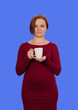 © Sergey - woman holding a white cup in her hands on a blue background