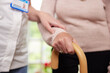 © Daisy Daisy - Close Up Of Senior Woman With Hands On Walking Stick Being Helped By Care Worker