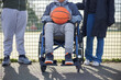 Close Up Of Teenage Girl In Wheelchair With Friends Playing Game Of Basketball In Park Together