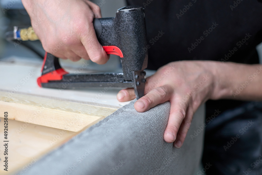 Stapper Working Worker qualitatively fixes the fabric with a pneumatic stapler on the ...