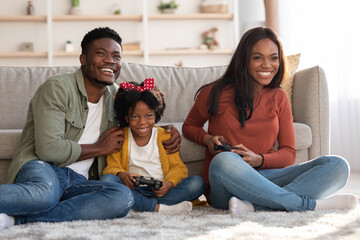 Family Pastime. Cheerful Black Parents Playing Video Games With Daughter At Home