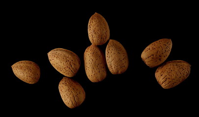 Wall Mural - Almond nuts in shells, kernels isolated on black, top view