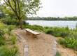 A handmade wooden bench surrounded by vegetation with a view over the lake at FDR Park in South Philadelphia, Pennsylvania, USA