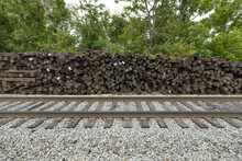 Brown Railroad Ties Piled Up Next To Active Train Tracks