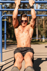 Strong handsome fitness man athlete with sexy muscular body workout outdoors