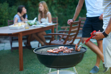 Wall Mural - The perfect summer lunch. Young guys barbecuing meat on the grill outdoors - Lifestyle.