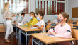 © JackF - Smart teenager in protective mask studying in classroom, listening to lecturer and writing in notebook