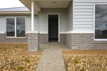 The front door and porch of a brand new timber weatherboard house. A classic Australian-style home. Concept of real estate investment, homeownership, and housing market. Melbourne, VIC Australia.