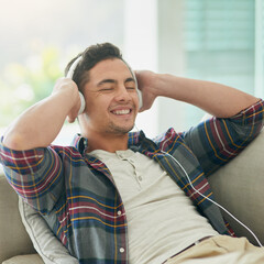 Sticker - Turn down the week, turn up the music. Shot of a young man relaxing on the sofa and listening to music with headphones at home.