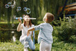 © hetmanstock2 - Young mother resting with her son in a park and blowing a soap bubbles