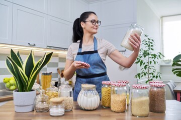 Wall Mural - Smiling woman in the kitchen with jars of stored food.