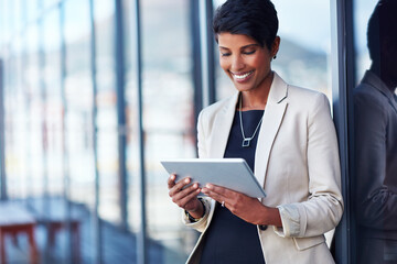 Making work more efficient and effortless with wireless technology. Shot of a young businesswoman using a digital tablet outside of an office building.