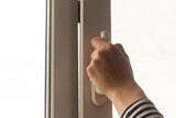 Fototapeta Mapy - A hand opens a window in an apartment or house for ventilation.