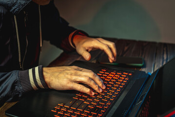 hands in type on a laptop keyboard in close-up. the concept of cybercrime fraud and identity theft