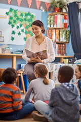 Wall Mural - Reading opens up their imaginations even further. Shot of a teacher reading to a group of elementary school kids in class.