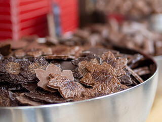 Dark chocolate confections with maple leaf shape in a confectionery store. In bulk sweets shop for indulgence, sugar treat and candy. Delicatessen tasty chocolates