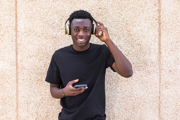 Sticker - Joyful young ethnic man smiling while listening to music in headphones