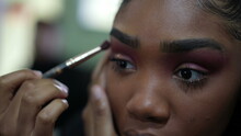 A Young Black Girl Applying Make-up In Front Of Mirror