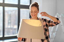 Moving, Electricity And Repair Concept - Woman Changing Light Bulb In Floor Lamp At New Home