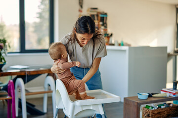 mother putting her baby in high chair