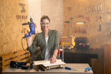 Portrait Of Woman Carpenter With Drill And Safety Goggles In Workshop
