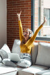© nenetus - Pretty woman celebrating something while working with laptop sitting on a couch at home.
