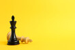 Leinwandbild Motiv Black king near fallen white one on yellow background, space for text. Game of chess